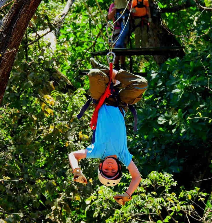 Guest on zipline adventure hanging upside down at the Congo Canopy Zipline in Playa Potrero, Guanacaste 